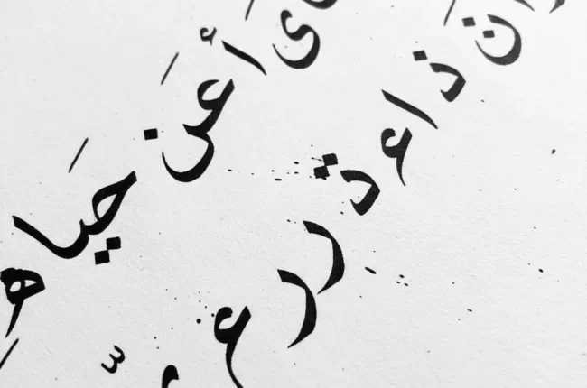 Diagonal scatter of black Arabic calligraphy on a white background, abstract and decorative.